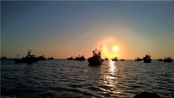 Mặt trời lặn kì ảo phía sau những chiếc thuyền đánh cá.